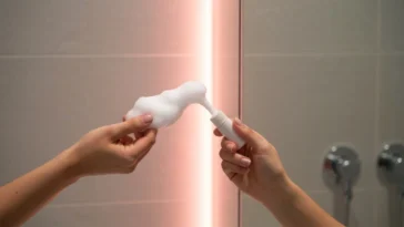 Mão segurando sabonete vermelho vibrante no banheiro moderno, com brilho dourado, simbolizando banho virada 2026 segredo.